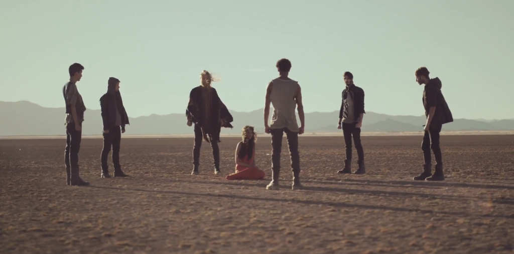 une femme entourée d'hommes les poings serrés qui laisse présager le pire