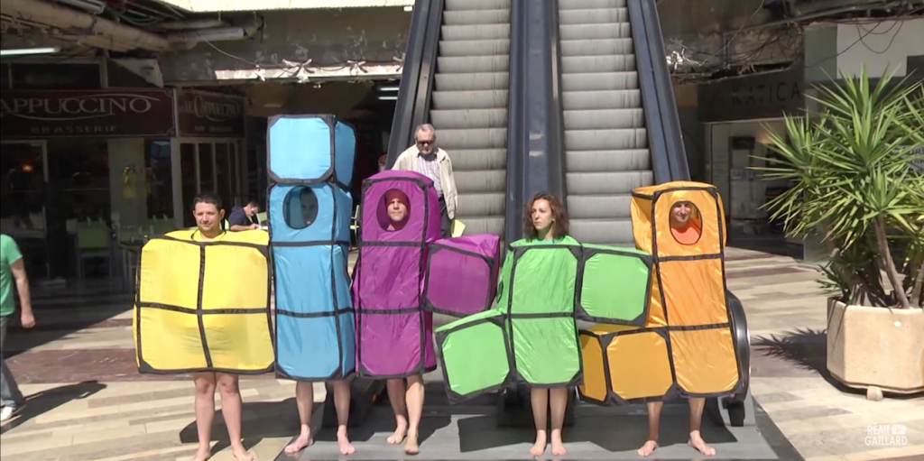 Déguisé en brique, Rémi Gaillard descend tranquillement de l'Escalator pour s'emboiter aux autres 